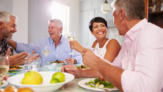 Group Of Mature Friends Enjoying Meal At Home Together
