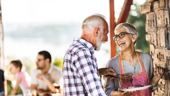Happy senior couple making barbecue for their family on a terrace.