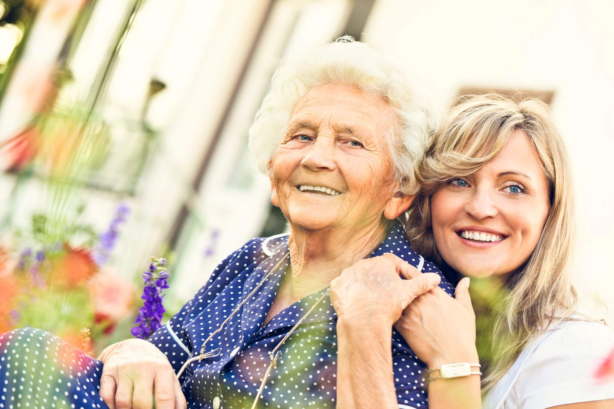 A younger woman hugging an older woman from behind