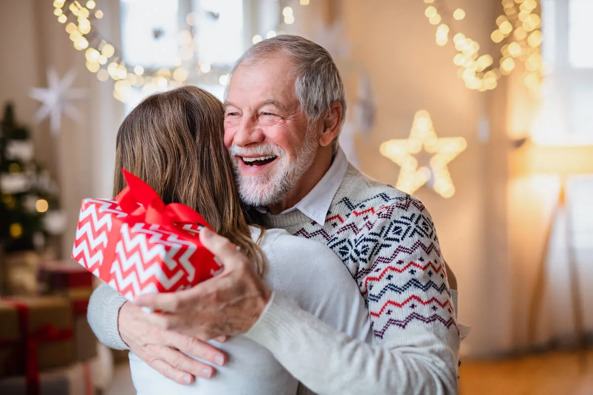 Happy older man receiving a Christmas present - Rockbridge Oaks Happy older man receiving a Christmas present