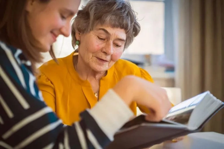 Adult daughter reading a book to her elderly mother with dementia