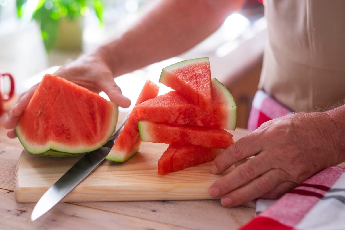 slicing watermelon - Rockbridge Oaks An older person slicing watermelon