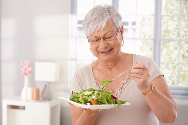 Happy older woman eating a salad